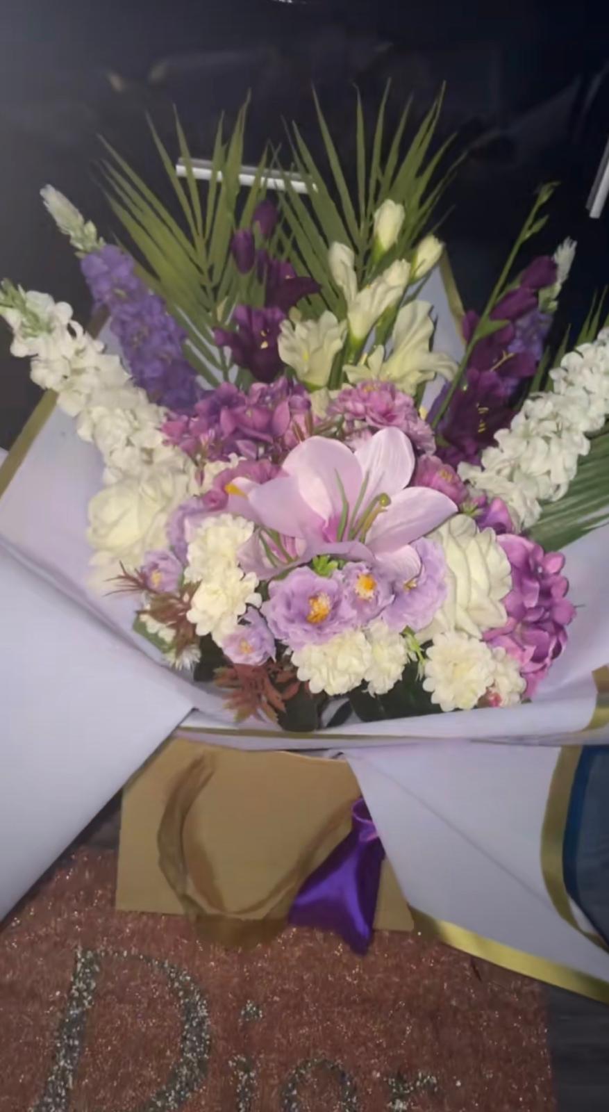 Tall artificial bouquet of lilac roses, purple gladioli, ivory stocks and a pink lily in white and gold wrap